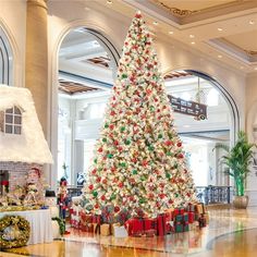 a large christmas tree in the middle of a lobby with presents on it's sides