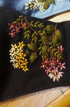 embroidered flowers on black fabric with yellow pins