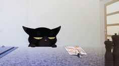 a black cat sitting on top of a table next to a book