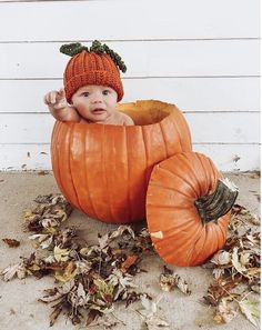 a baby in a pumpkin costume sitting on the ground