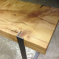 a wooden table with metal legs and a wood slab on the floor next to it