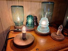 three glass jars sitting on top of a wooden table next to a small light bulb