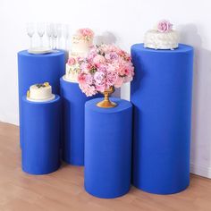 there are three blue cylinders with flowers on them and one cake in the middle,