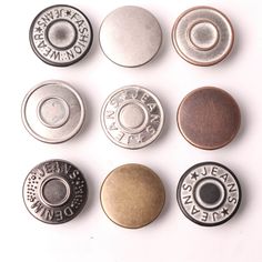 six different types of metal buttons on a white surface with one button facing the camera