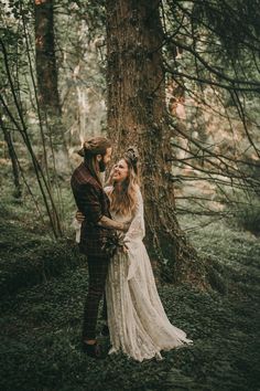 a bride and groom standing next to each other in the woods