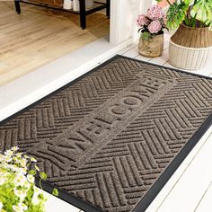 a door mat with the words welcome home on it in front of a potted plant