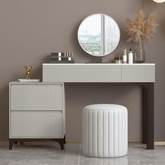 a vanity with a mirror, stool and vase on it next to a round mirror