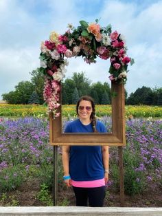 a woman standing in front of a frame with flowers on it