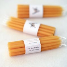 three orange candles with labels on them sitting next to each other