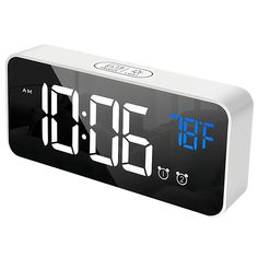 the alarm clock is white and black with blue numbers on it's display screen