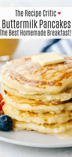 a stack of pancakes with butter and blueberries on a white plate next to a glass of orange juice