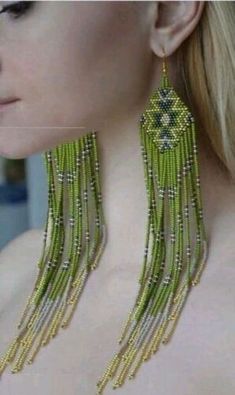 a woman wearing green beaded earrings with fringes on her neck and back, in front of a white background