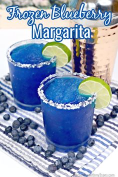 two blueberry margaritas are garnished with lime and sugar on the rim