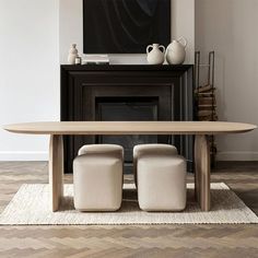 a table with two stools in front of a fireplace