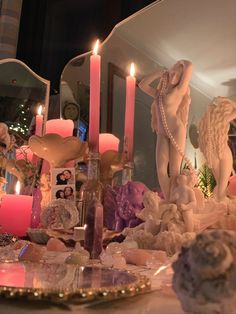 a table topped with candles and figurines on top of a table covered in shells