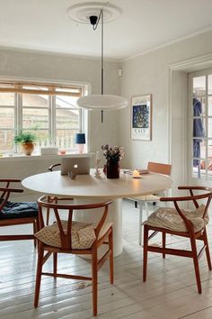 a dining room table with four chairs and a laptop on the table in front of it