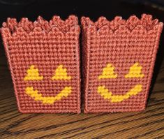 two knitted bags with faces on them sitting on a wooden table next to each other