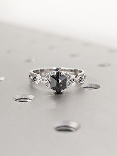 a black diamond ring sitting on top of a metal surface with drops of water around it