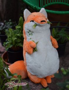 an orange and white stuffed animal sitting in front of potted plants with eyes closed