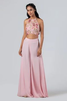 Light pink padded crop top with halter neckline, floral print on the base and embroidered motifs in a floral pattern. Comes with flared pants. Component: 2 Pattern: Print and Embroidery Type Of Work: Floral Print, Sequin, Cutdana, Beads and Thread Neckline: Halter Sleeve Type: Sleeveless Fabric: Crepe and Georgette Crepe Color: Pink Other Details:  Crop top with floral print panel at the back Tie up at the back Closure: Crop top: Back hook Occasion: Destination Wedding - Aza Fashions Traditional Crop Top And Pant, Top And Plazo Indian, Plazo With Crop Top Western, Plazo Top Western, Blouse And Plazo Set, Flared Plazo Designs, Plazo And Top Western, Plazo And Top