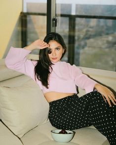 a woman sitting on top of a couch next to a bowl of fruit