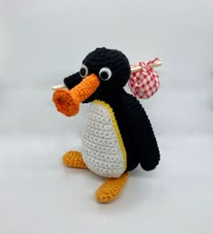 a crocheted penguin with a red and white checkered bow