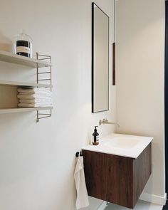 a bathroom with a sink, mirror and shelving unit on the wall above it