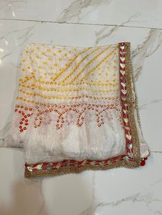 "WELCOME TO MY SHOP  Product Detail :- Handmade Item Item Name :- Bandhani Dupatta Material :- Silk, Tie Dye Size :- Length- 88 inch , width- 44 inch Color :-  White Rajasthani Bandhej Dupatta Silk Bandhani Bandhej Women Heavy Dupatta with Gota Work and latkan Bridal Dupatta. 100% Brand New And High Quality Scarf Suitable For Personal Wearing or Gift Ideal For Friends And Your love One. Great to match any fashion style. NOTE : Product color may slightly vary due to photographic lighting sources or your monitor settings. Explore our diverse collections: 👜 Potli / Bags - [Shop Potli/Bags](https://www.etsy.com/shop/Mgemsandjewels?ref=seller-platform-mcnav§ion_id=39185383) 🧣 Dupattas / Scarves - [Shop Dupattas/Scarves](https://www.etsy.com/shop/Mgemsandjewels?ref=seller-platform-mcnav§ion_id Bandhej Dupatta, Tie Dye Scarf, White Silk Scarf, Bandhani Dupatta, Heavy Dupatta, Bridal Dupatta, Tie Dye Scarves, Gota Work, Potli Bags