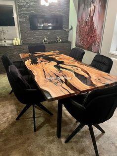 a dining room table with black chairs and a large painting on the wall behind it