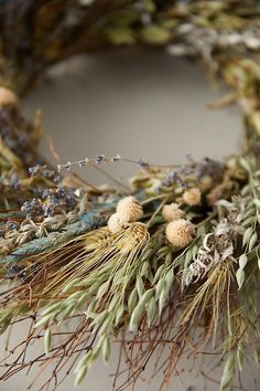 an arrangement of dried flowers and herbs on a white table top with the stems still attached to the wreath