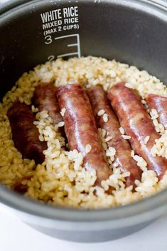 three sausages and rice in a pot on the stove