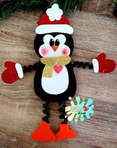 a penguin wearing a santa hat and scarf on top of a wooden table with christmas decorations