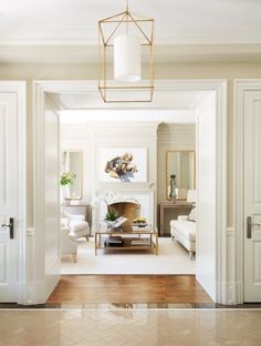 a living room with white walls and gold accents on the ceiling, along with an open door leading to another room