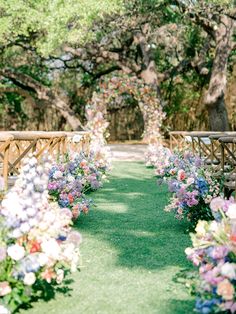 an outdoor ceremony with rows of wooden chairs and flowers lining the aisle, all lined up