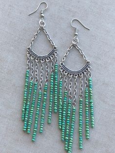 a pair of earrings with beads hanging from it's sides on a white surface