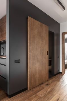 an open door in the middle of a room with wood floors and black painted walls