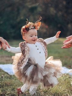 a baby girl in a tutu is holding her mother's hand