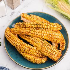 grilled corn on the cob in a blue plate next to fresh parsley