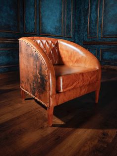 a brown leather chair sitting on top of a wooden floor next to a blue wall