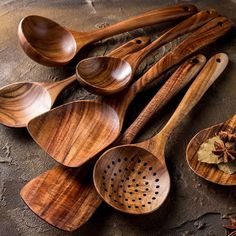 wooden spoons with holes in them and spices on the ground next to them,