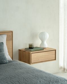 a bedroom with a bed, night stand and lamp on the nightstand next to it