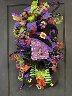 a halloween wreath on the front door decorated with colorful ribbons and decorations, including a witch's hat