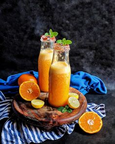 two glasses filled with orange juice and garnished with mint on a wooden platter