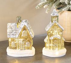 two small gold and white christmas houses on a table