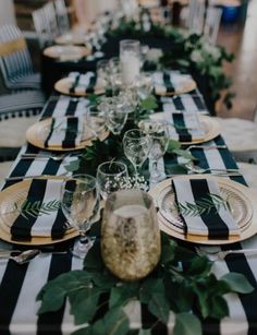 a long table with black and white striped runneres, greenery and gold place settings