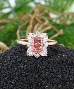 a pink diamond ring sitting on top of a rock