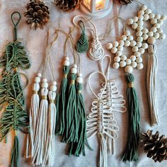 various tassels and pinecones are arranged on a white tablecloth next to a lit candle