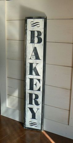 a wooden sign that says bakery on the side of a wall next to a door