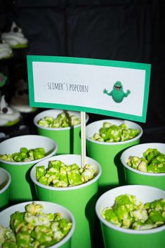 green cups filled with food sitting on top of each other in front of a sign that says slimmer's popcorn