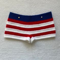 a red, white and blue knitted shorts with stars on the side sitting on a wall